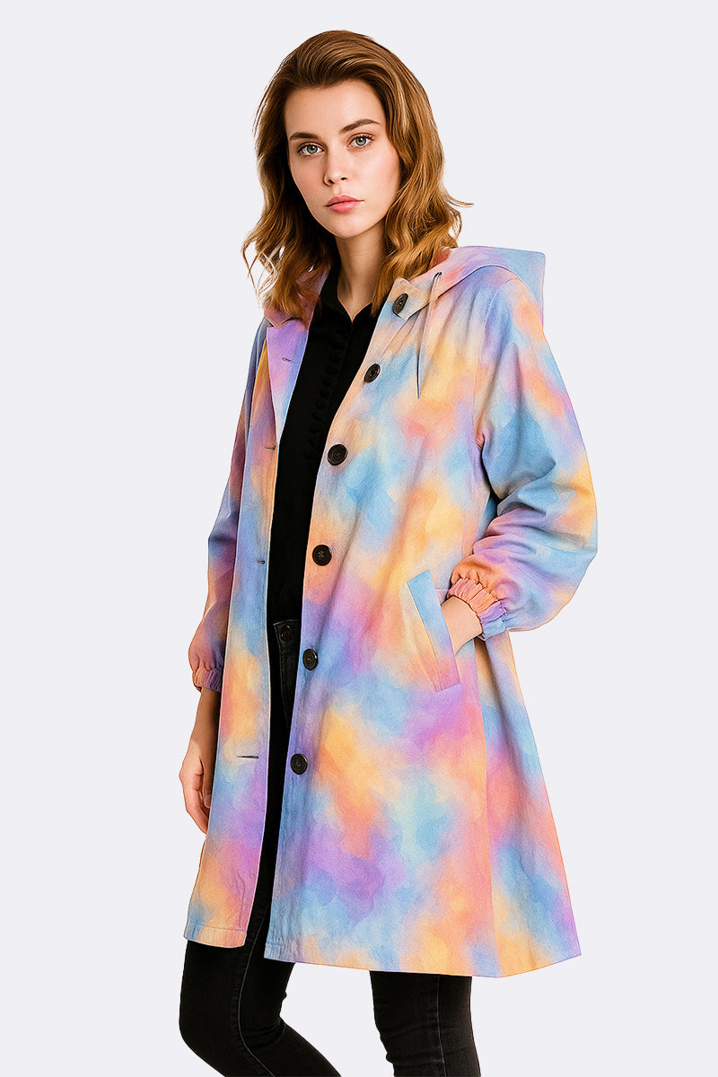 A person wears the looselyboho CANVAS SKY WINDBREAKER, a pastel tie-dye hooded jacket with black buttons and pockets, standing forward and slightly angled against a plain light background.