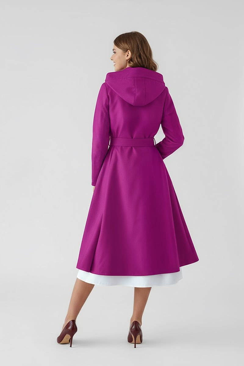 A woman faces away from the camera, modeling the looselyboho Water-Repellent Rain & Shine A-Line Hooded Raincoat in vibrant magenta, styled with heeled shoes and a white skirt, against a simple light backdrop.