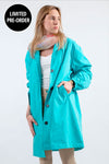 A person in a looselyboho ELECTRIC CYAN WINDBREAKER with an adjustable hood, a white shirt, beige pants, and a colorful scarf looks to the side. A "Limited Pre-Order" label appears in the top left corner.