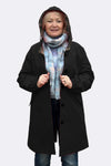 A person poses against a plain background wearing looselyboho's LUXE BLACK WATERPROOF WINDBREAKER with plaid interior. The windbreaker is unbuttoned, revealing blue jeans, and the individual holds its edges while showcasing the adjustable hood and a blue scarf.