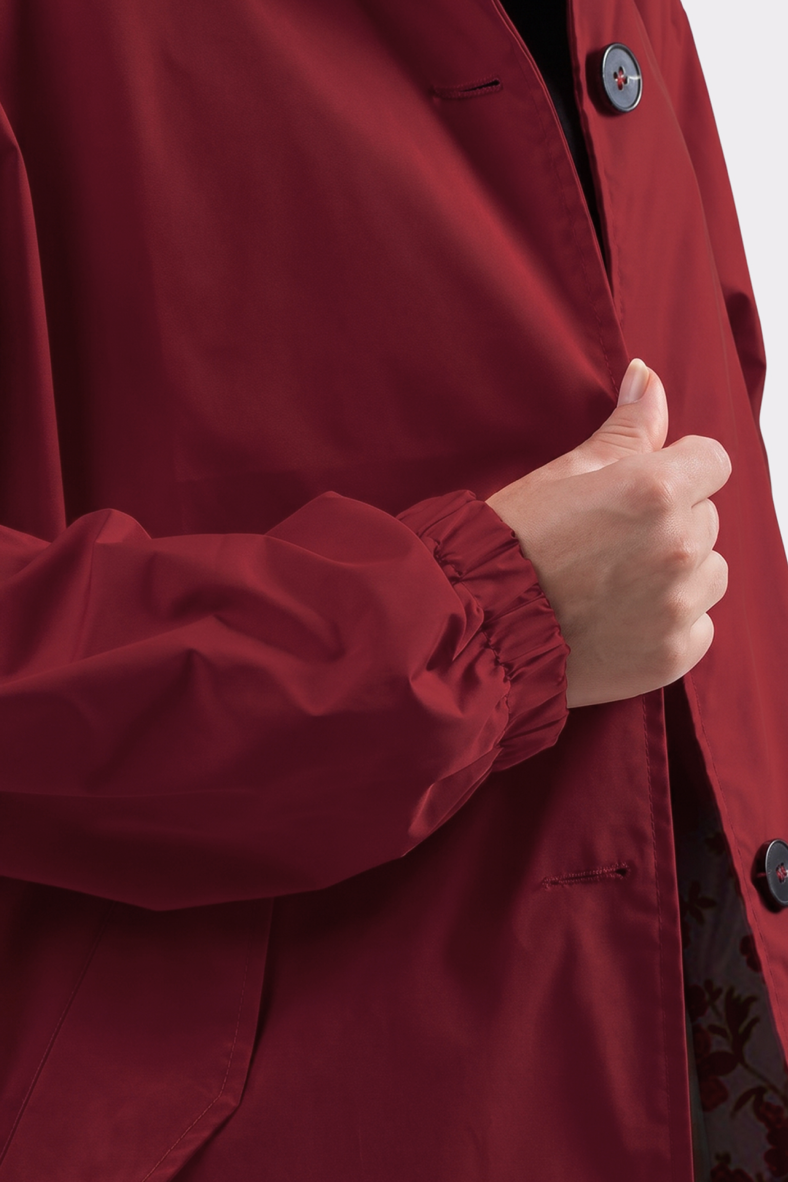 A person in The Water Resistant Hooded Oversized Windbreaker Rain Jacket holds the front edge with one hand, highlighting the button and elastic wrist cuff.