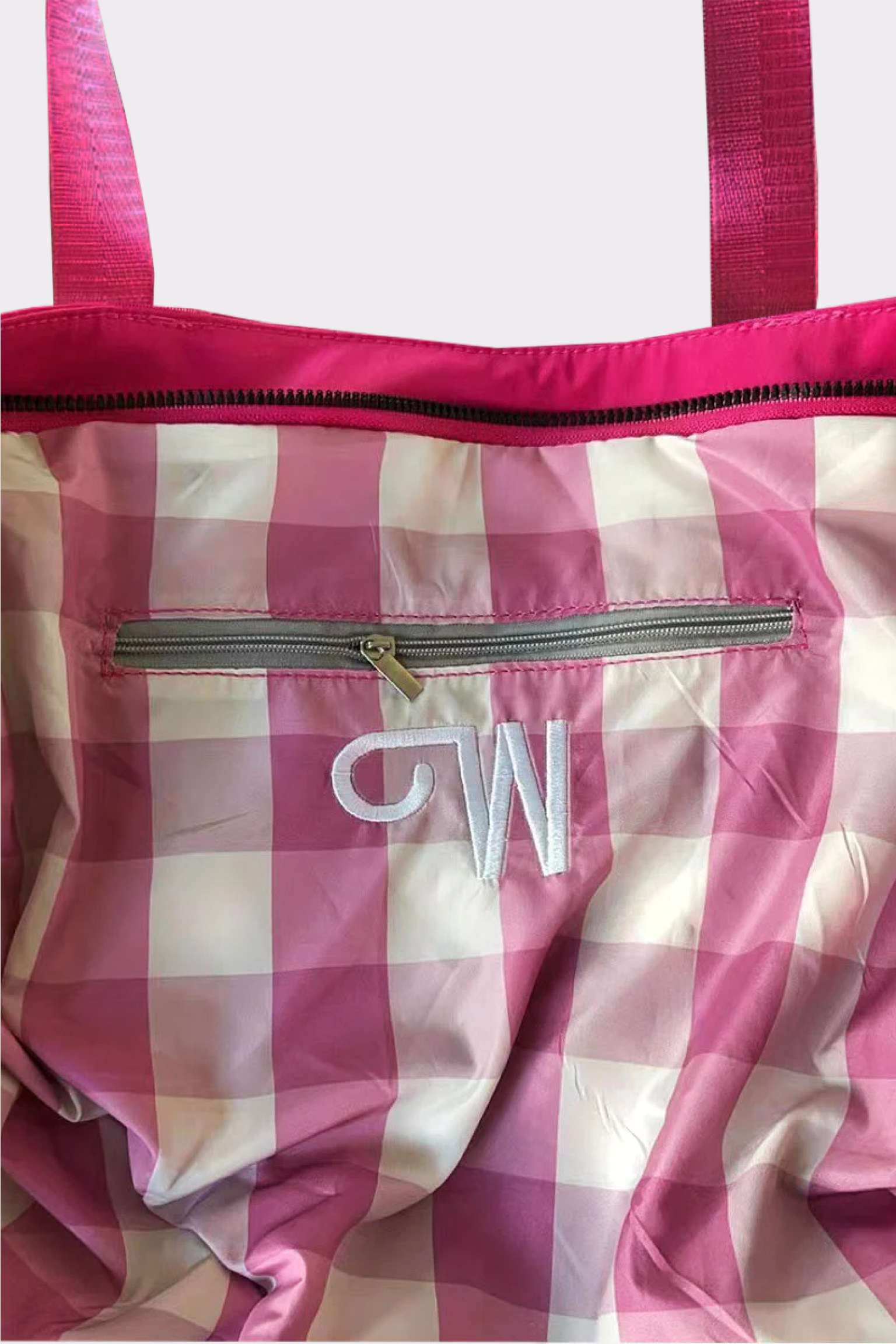 The Urban Slate Waterproof Bag is a pink and white checkered gym and travel bag with a pink zipper, pink handles, an inner zip pocket, and “CW” embroidered in white—perfect as a stylish duffel for your essentials.