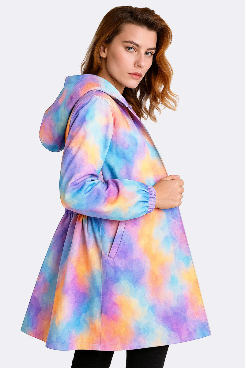 Wearing the looselyboho CANVAS SKY WINDBREAKER, which features a vibrant watercolor pattern in blue, purple, orange, and yellow, a person stands slightly to the side against a simple light backdrop.