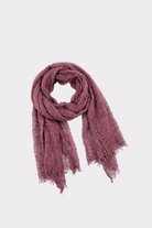 The Lightweight Linen Scarf, in muted mauve, features a textured crinkled design with loosely gathered and slightly frayed ends, offering ultra-breathable comfort and versatile style for any occasion.