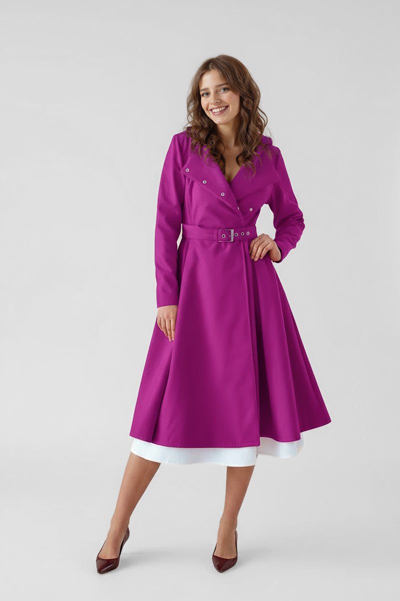A woman stands against a plain light background, wearing the looselyboho Water-Repellent Rain & Shine A-Line Hooded Raincoat in magenta over a white hem with dark pointed-toe heels. She smiles confidently, one hand on her hip.