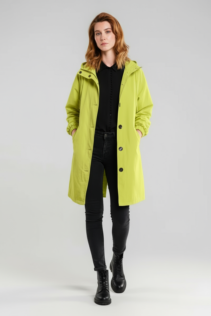 A person with shoulder-length light brown hair models the looselyboho SUNLIT YELLOW WINDBREAKER over a black outfit and black lace-up boots, standing against a plain light gray background.